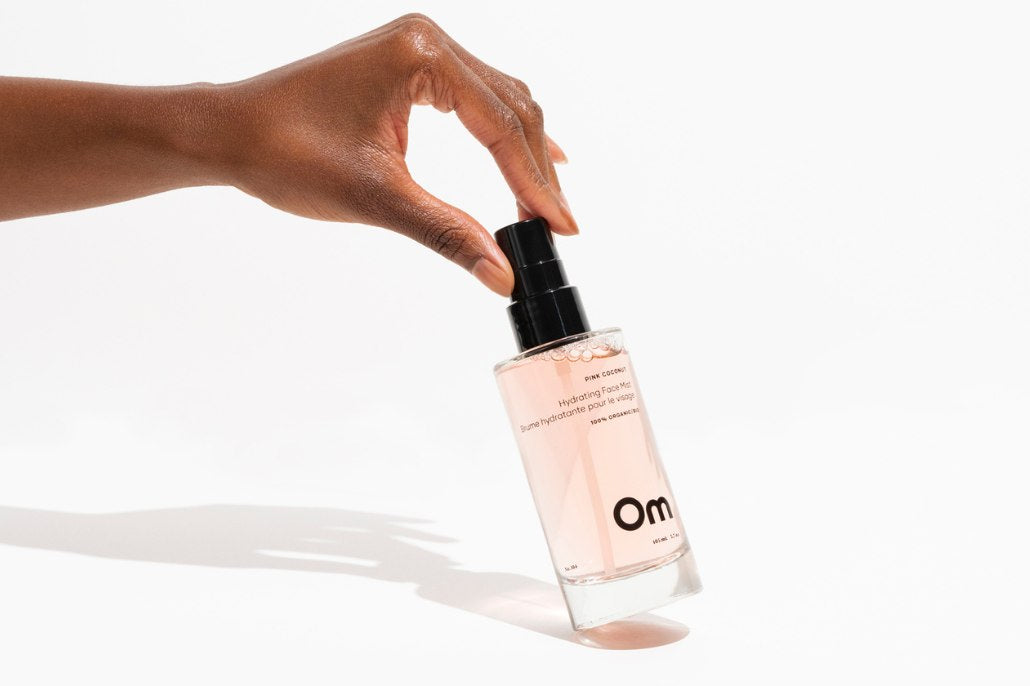Close up of Om Organics Hydrating Mist and a young woman’s smile.