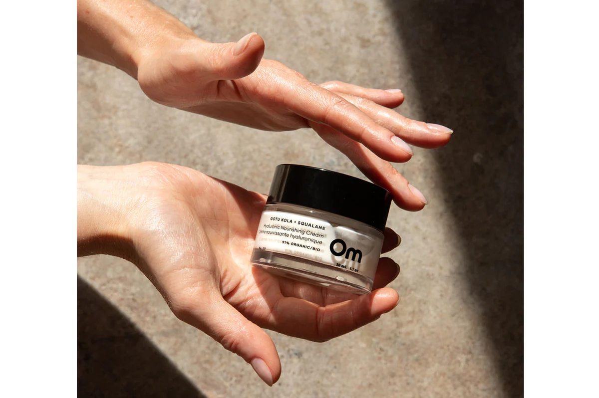 Hands holding the Om face cream in soft sunlight